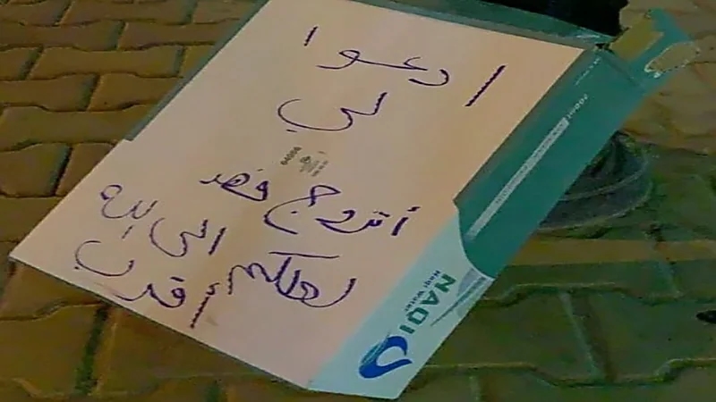 فتاة تكتب على كرتونة مياه وضعتها في ممشى كصدقة جارية: " أدعو لي أتزوج فهد "