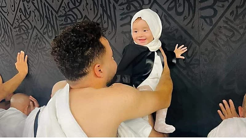 صورة مؤثرة لطفلة رضيعة تبتسم لوالدها أثناء لمسها الكعبة