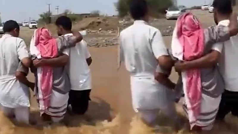 شابان يقطعان السيول مع والدهما مشيا على الأقدام للذهاب لموعد غسيل الكلى .. فيديو