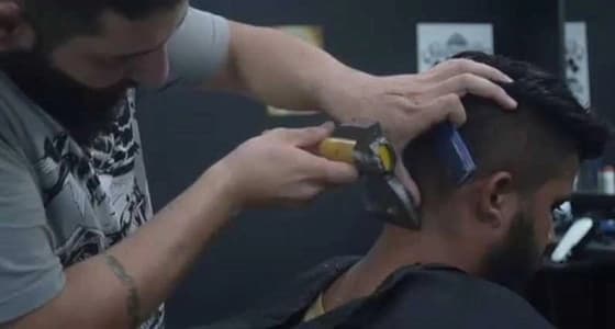 بالفيديو.. سوري يحلق لزبائنه بالمطرقة والبلطة يثير دهشة المتابعين